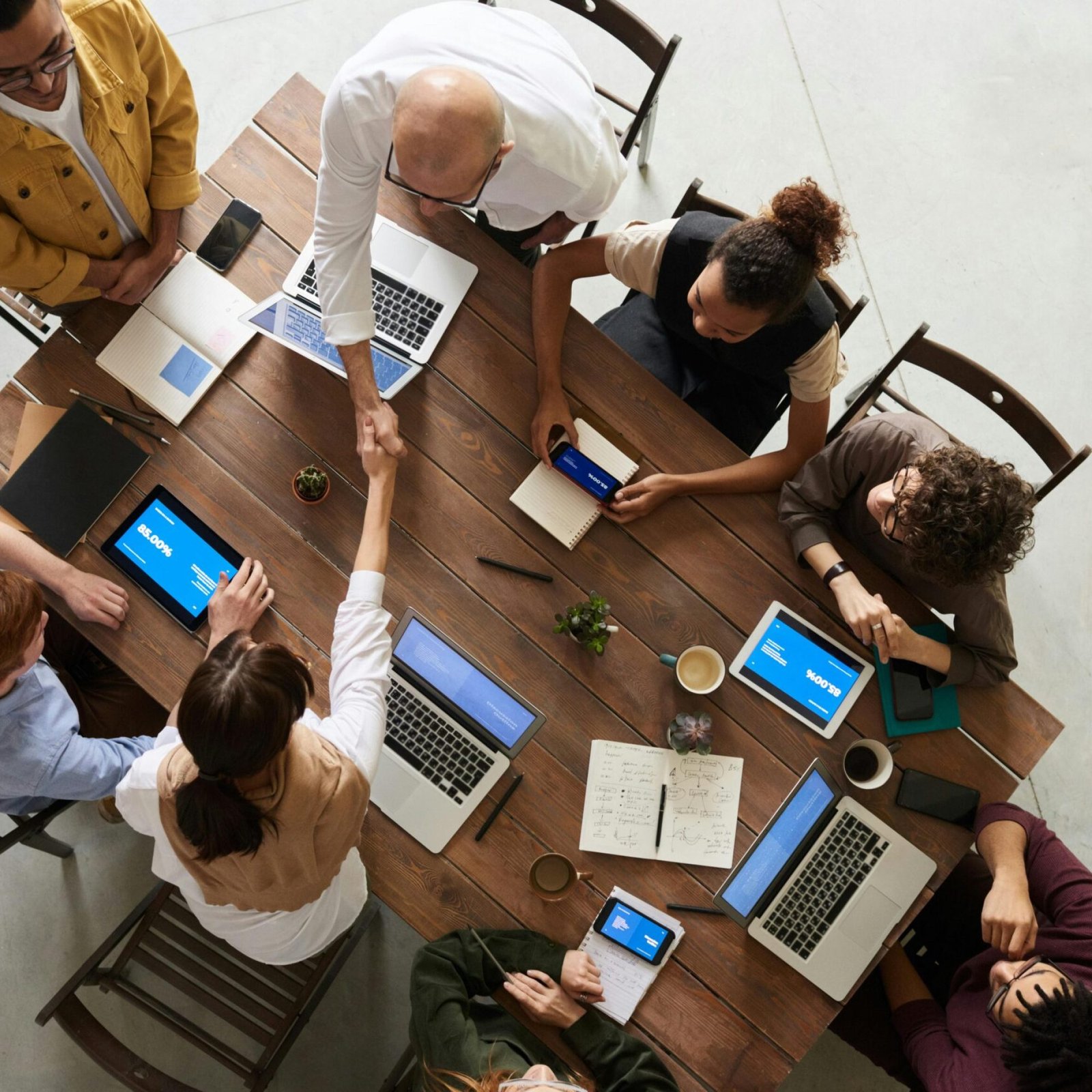 pexels-photo-3183197-3183197 Top view of a diverse team collaborating in an office setting with laptops and tablets, promoting cooperation.